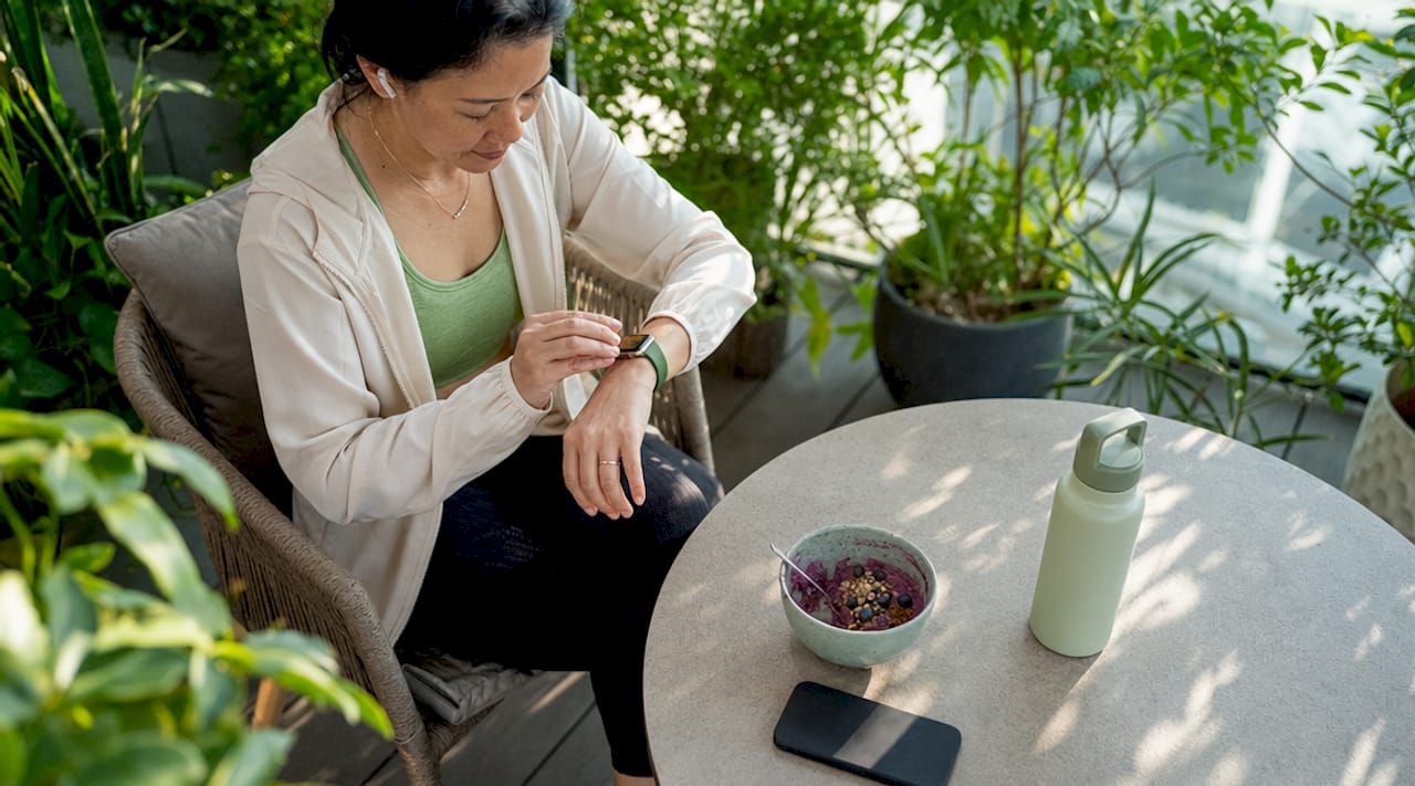 Woman checking wearable health device at home