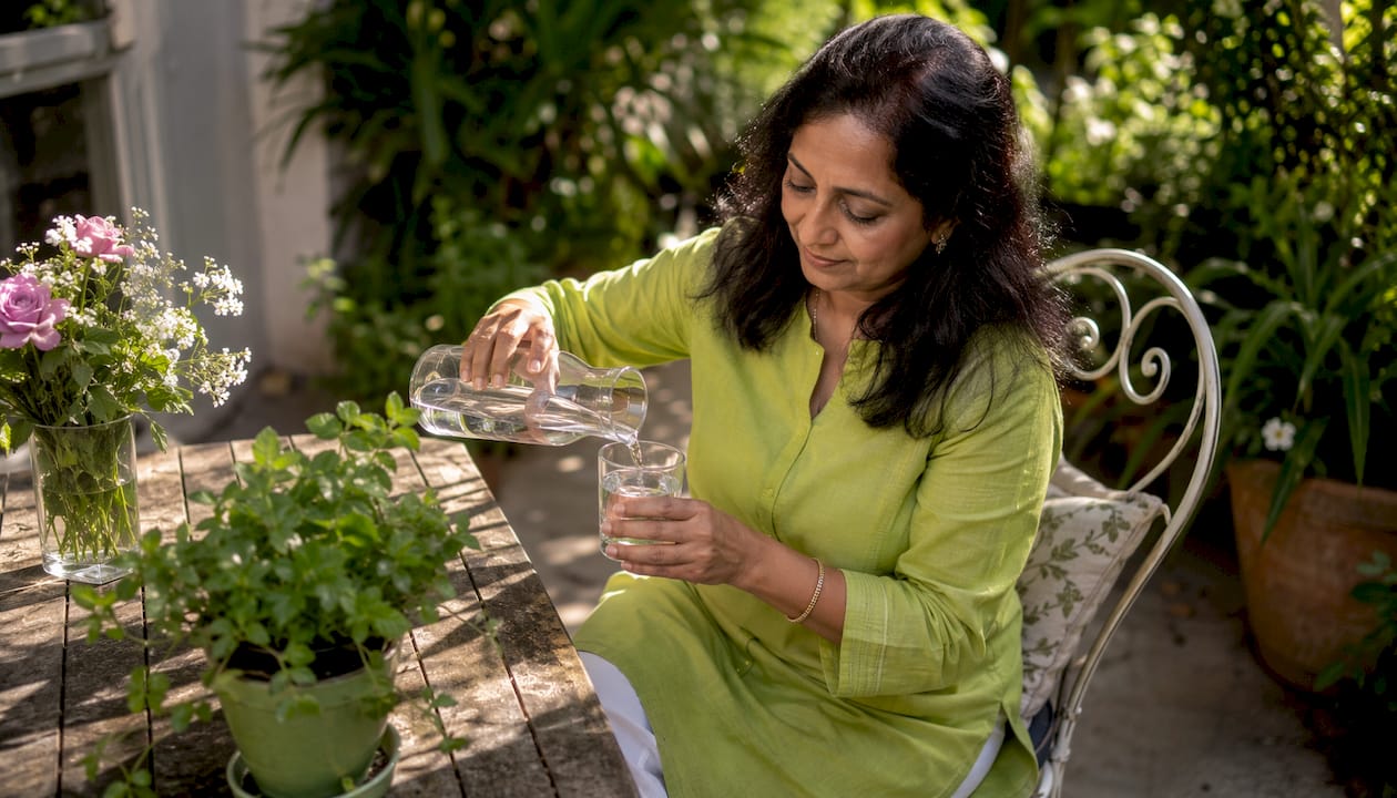 Woman pouring water in sunlit kitchen