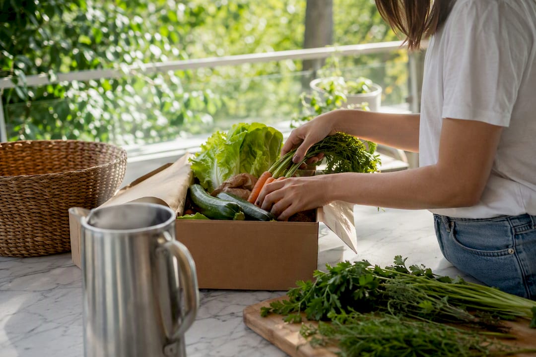 Hands unpacking fresh organic vegetables at home